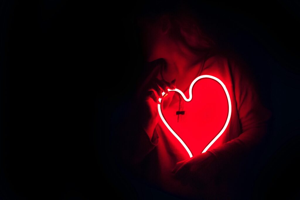 A woman holding a red neon light in the dark showing a fearful avoidant vs dismissive avoidant. 